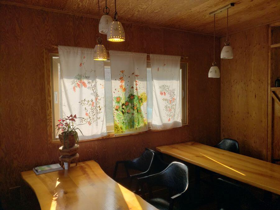 A room with wooden tables and walls with a window and curtains